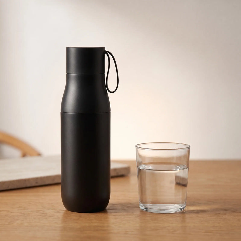 The smart water bottle beside a glass of water
