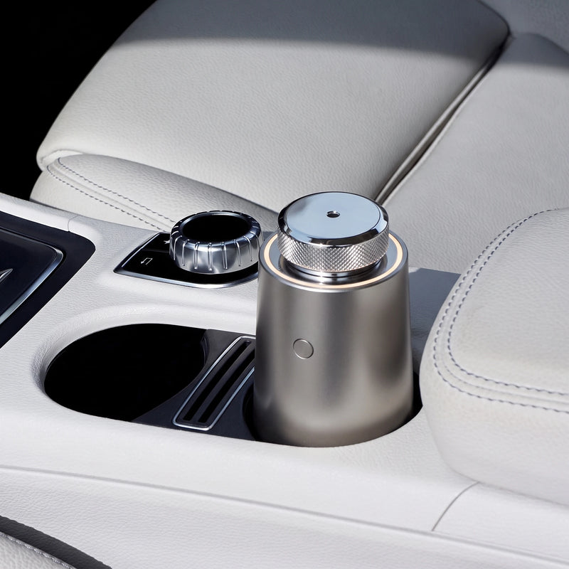 The car diffuser in Stone Grey in the cup holder of a cream leather console, in daylight