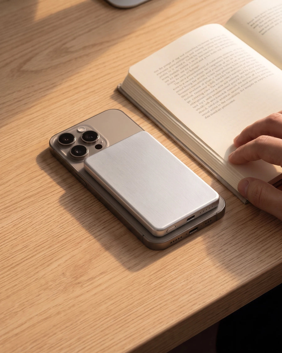 The slab on the back of a phone lying on a desk beside an open book