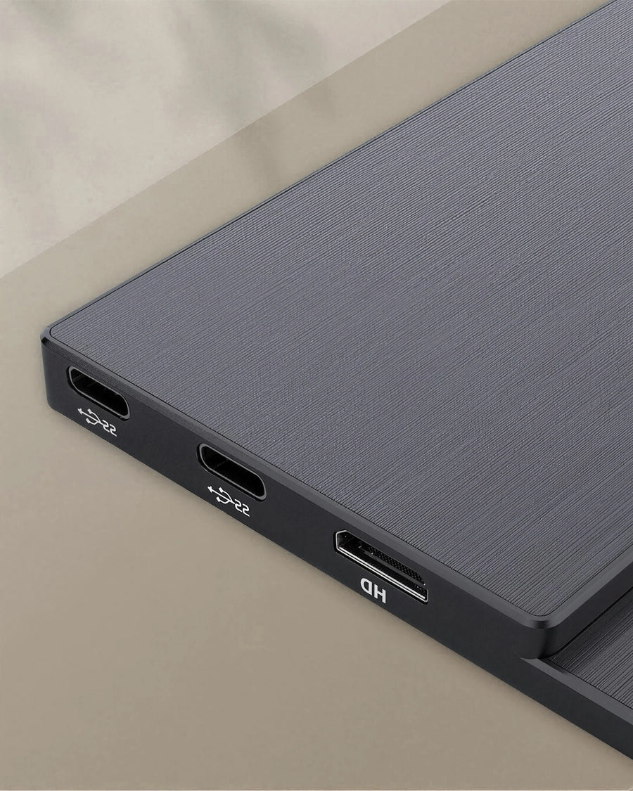 Macro of the data edge of the portable monitor: two full-function USB-C sockets and the video input, on a warm sand backdrop