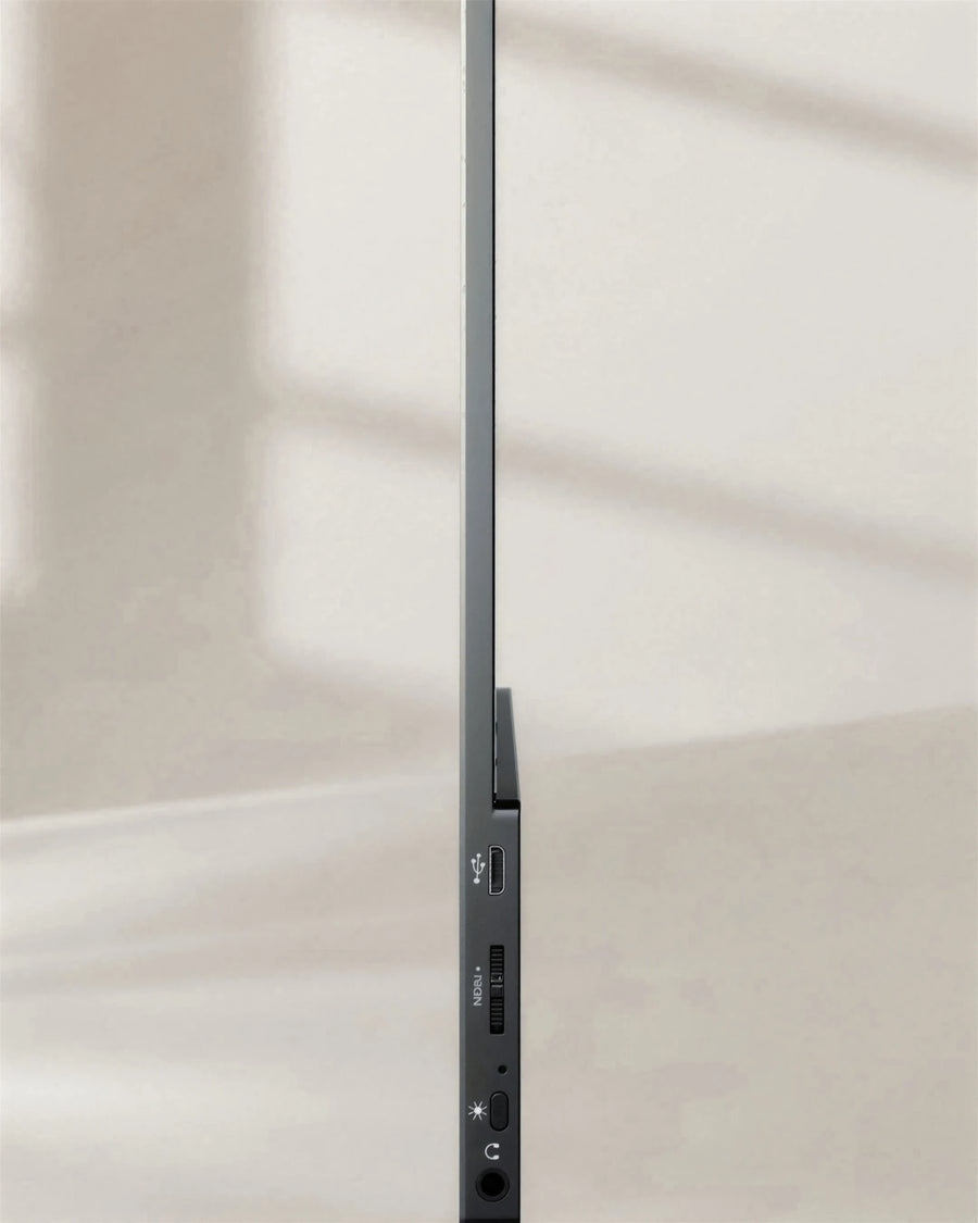 The portable monitor seen edge-on, about 5 mm thin, with the scroll wheel, multifunction button and headphone jack on the controls edge