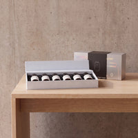 The open box of six bottles on a concrete table