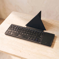 The folding keyboard in Ink with its case, on travertine