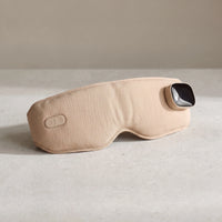 The Unwind heated eye massager in Earth on pale limestone