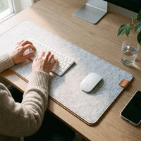 Felt & Cork Desk Mat in Ash under a keyboard and a mouse as someone types at a home desk