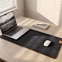 Felt & Cork Desk Mat in Charcoal on an oak desk in afternoon light, with an open laptop and a mouse