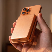 The power bank in copper, 10000mAh height, on the back of a matching copper phone, its blank side outward