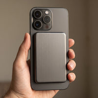 The power bank in dark gunmetal on the back of a dark grey phone, its blank side outward