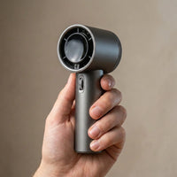 The handheld fan — held upright in one hand