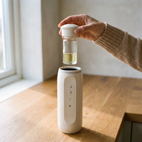 A hand lifting the oil bottle and cap straight up out of the diffuser