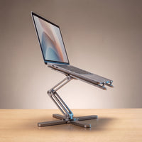 The folding laptop stand in Space Grey, holding a laptop at eye level