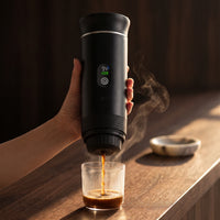 The portable espresso maker mid-brew, espresso running into the cup